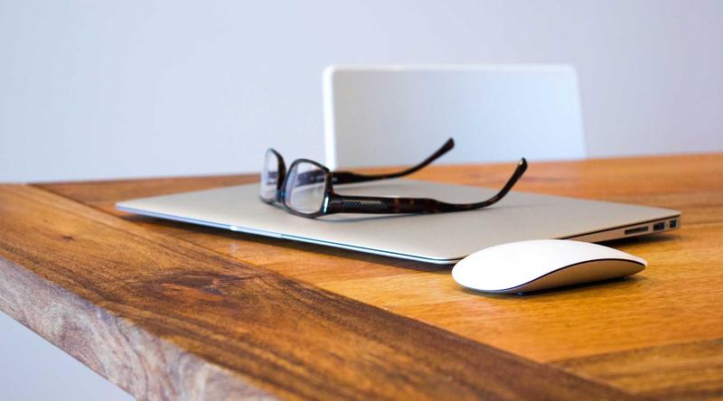 A desk with a laptop and reading glasses
