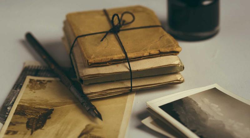 A bundle of documents tied with string, beside a pen